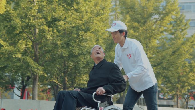 年轻志愿者帮助老年人推轮椅