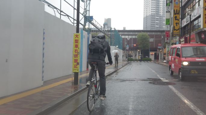 自行车信使在多雨的街道骑行