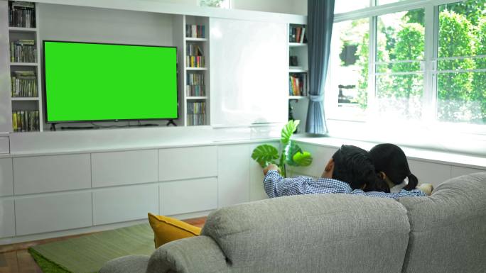 快乐家庭在客厅使用绿色屏幕显示器观看电视