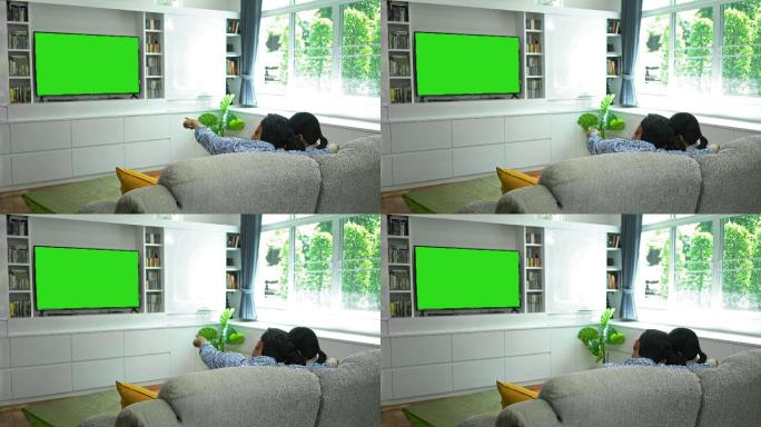 快乐家庭在客厅使用绿色屏幕显示器观看电视