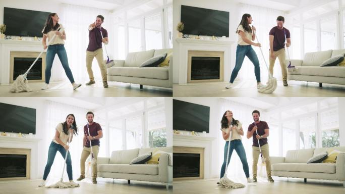 一对年轻夫妇在家打扫客厅时唱歌跳舞