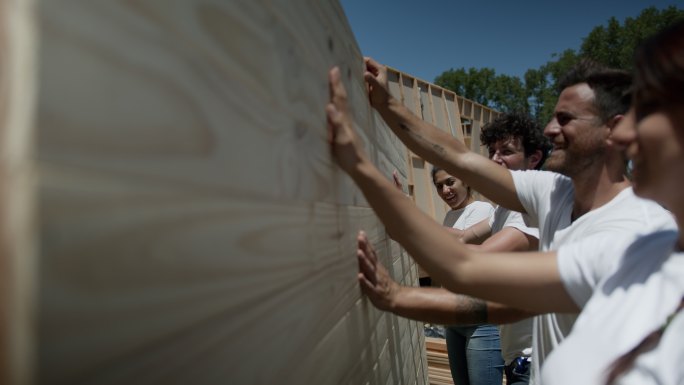 一组志愿者在慈善建筑工地摸着一堵沉重的墙
