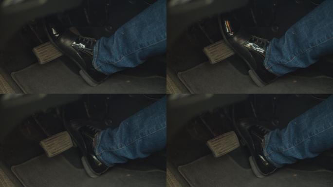 穿着黑色皮鞋的男性腿部踩下制动踏板