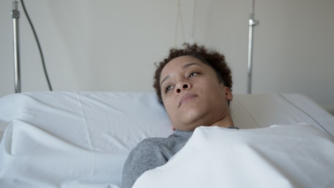 女病人躺在病床上，很孤独地看着别处