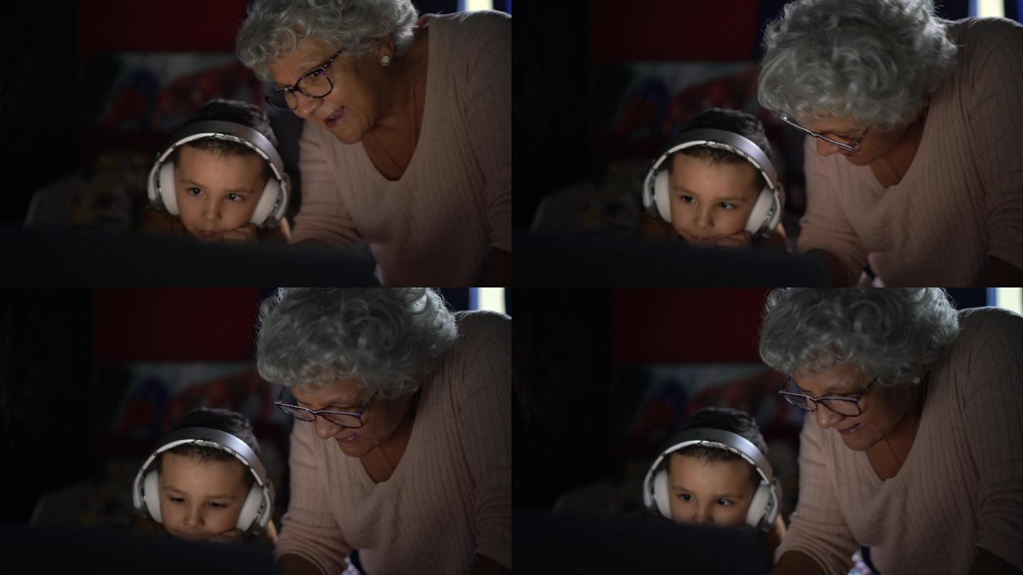 祖母和孙子在家使用笔记本电脑