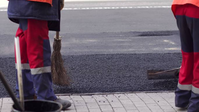 压路机和工人对城市街道进行沥青铺筑和维修