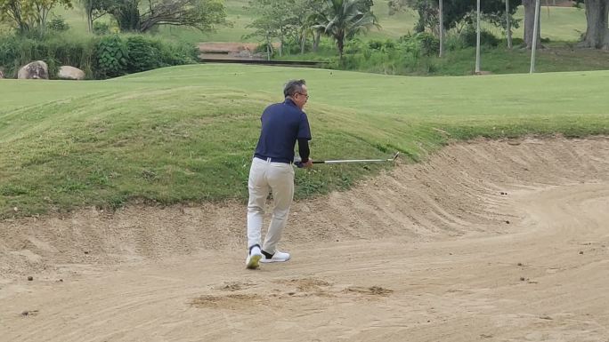 男子高尔夫球手在沙坑中用铁棒击球失败