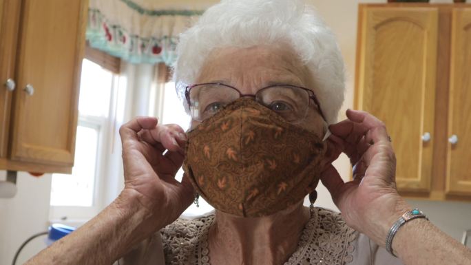 家庭住宅厨房戴布口罩的老年女性