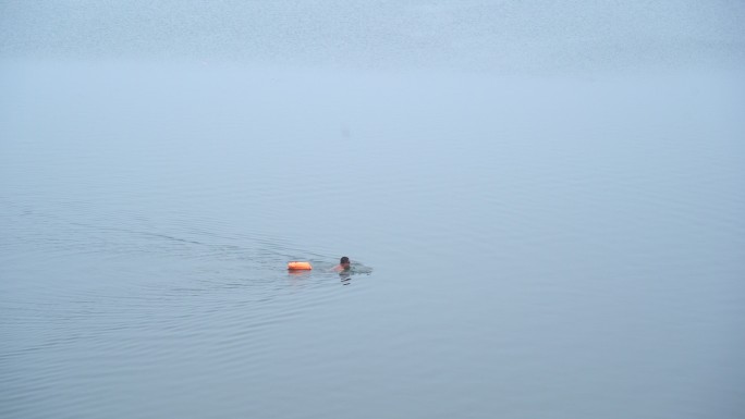 冬泳者穿着安全设施在湖里游泳4K