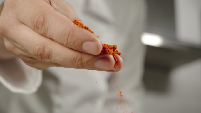慢动作：厨师在烹饪时撒上红辣椒粉