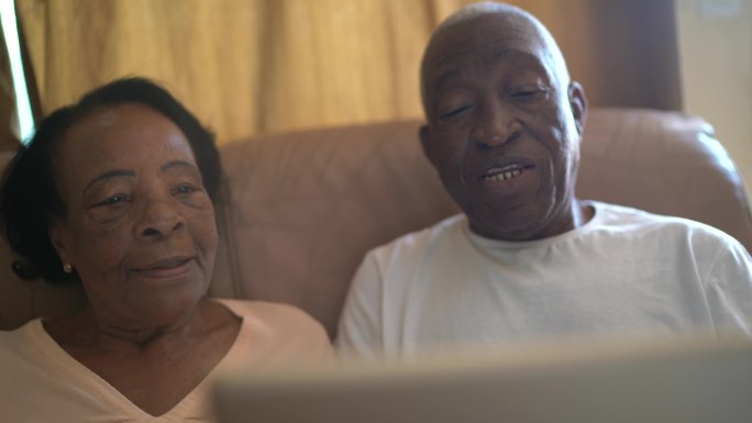 一对老年夫妇在家里使用数字平板电脑进行视频通话