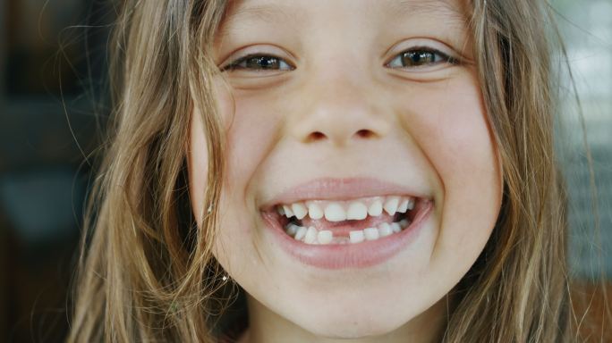 小女孩在屋外用腐烂的牙齿对着镜头微笑