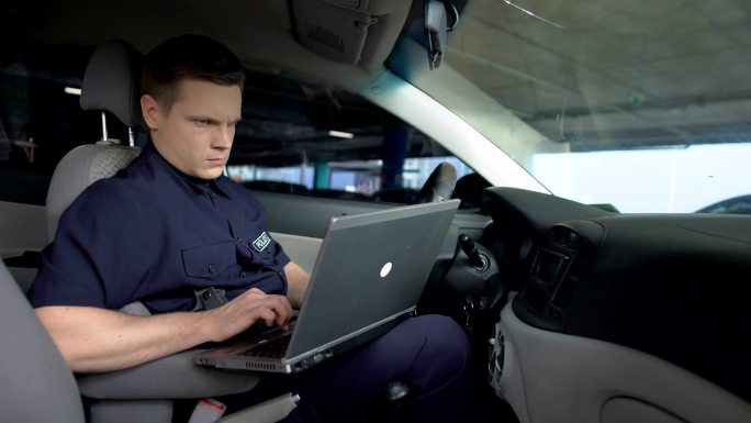 在车内使用笔记本电脑的警察