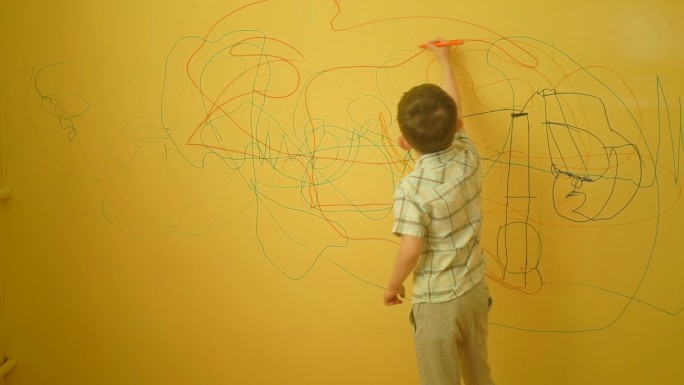 男孩在家里的黄色墙上画画