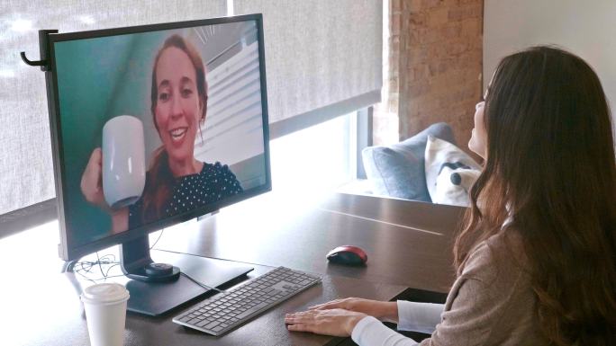 年轻女性使用台式电脑与她的朋友进行虚拟交