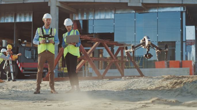 两名专家在一个建筑工地控制无人机。