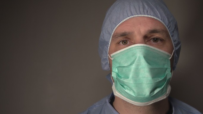 医护人员带着面罩和发网看着摄像机