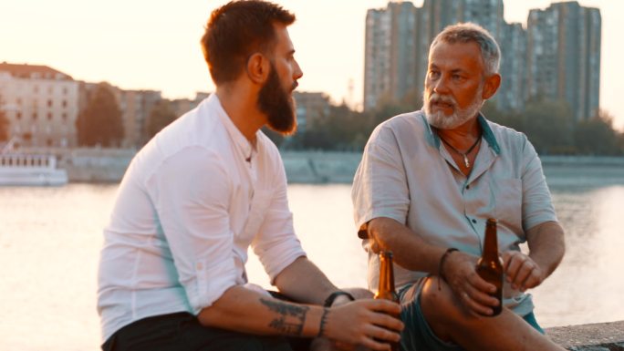 父子俩坐在河边聊天谈心交谈