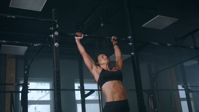 一名女性在健身房做引体向上。
