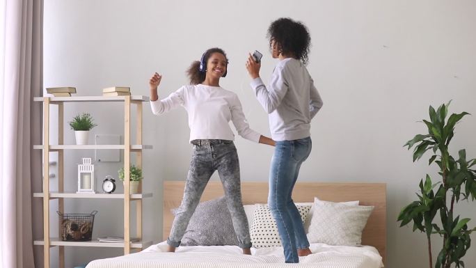 混血母亲和女儿在床上欣赏音乐跳舞