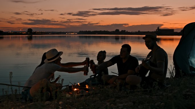 黄昏时分，一群年轻人在湖边露营