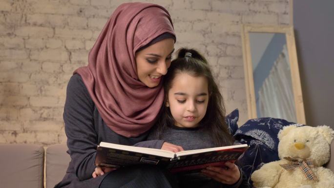 母亲教女儿阅读。阿拉伯女子戴头巾女子妇女