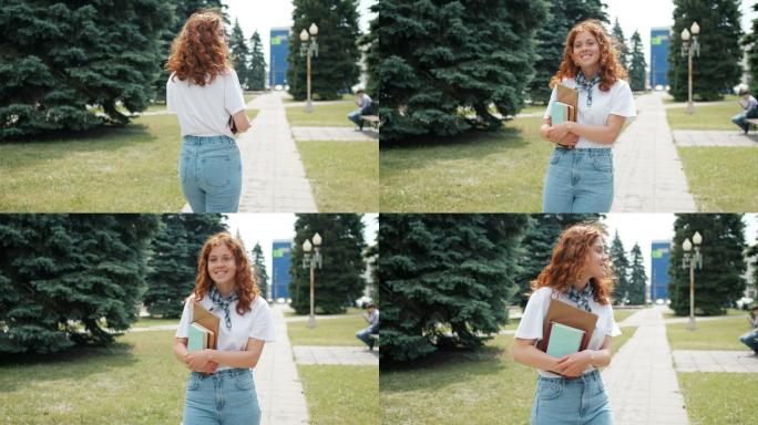 女孩拿着书走在户外，然后转向相机微笑