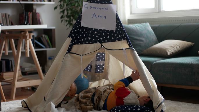 一个小男孩在家里的帐篷内玩耍