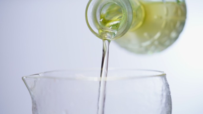 特写透明的橄榄油倒入杯子