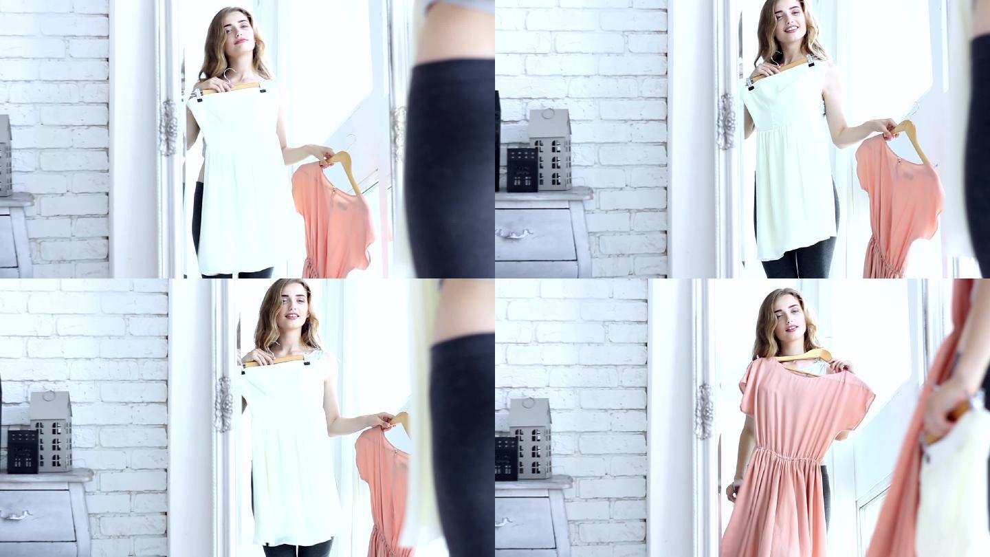 在大镜子前试穿白色和粉色连衣裙的女人。