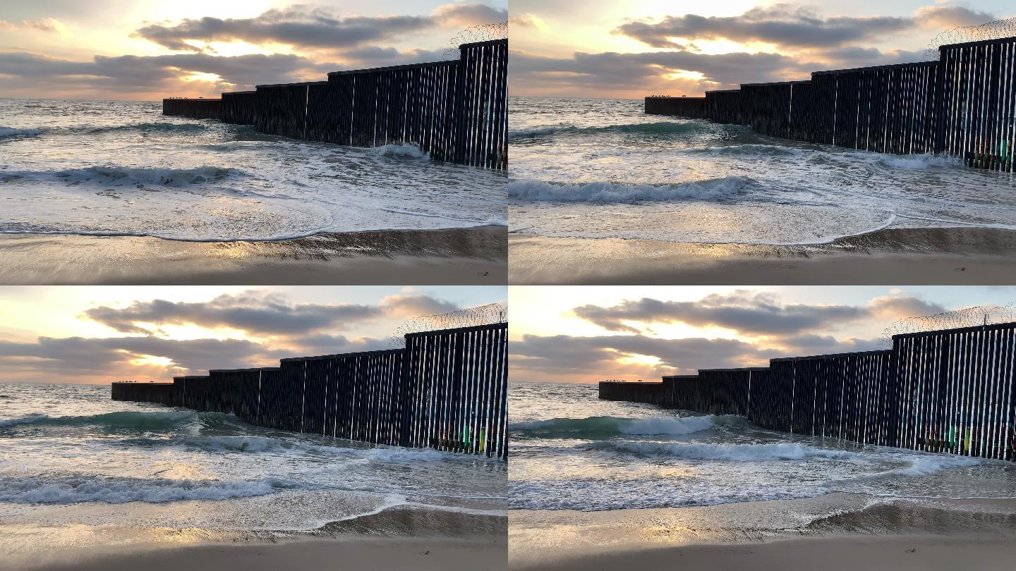 国际边界墙附近日落时的海滩和海浪