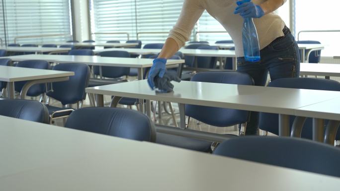 清洁女工给学校教室的桌子消毒