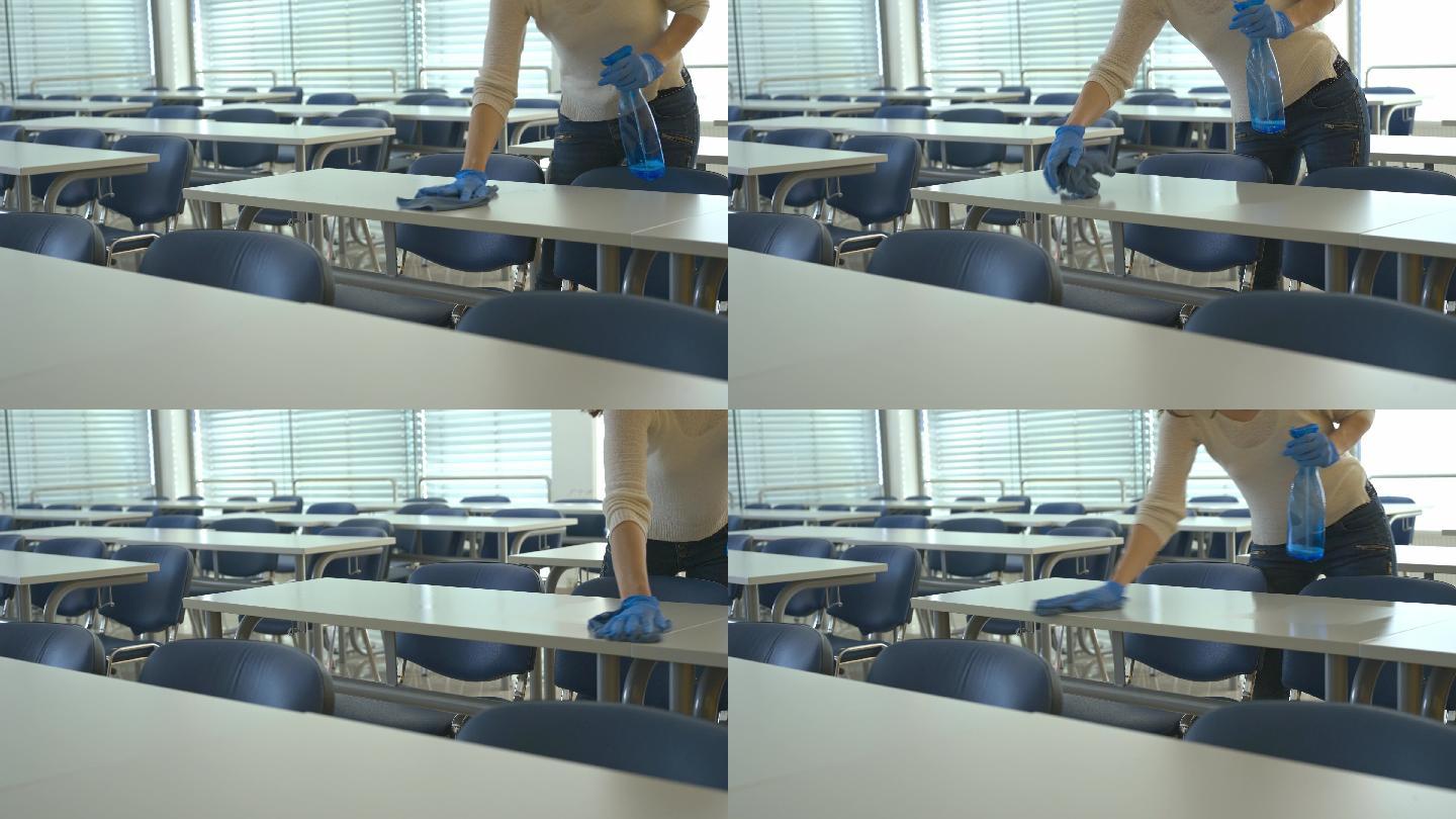 清洁女工给学校教室的桌子消毒