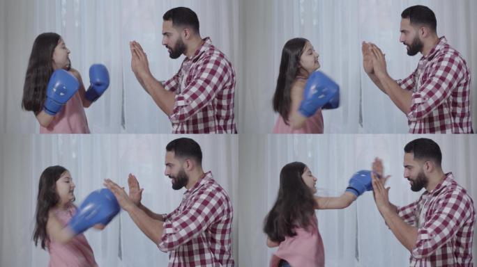 小女孩在室内拳击父亲的手的侧视图。