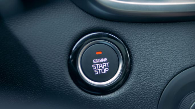 男性驾驶员按下按钮启动发动机。