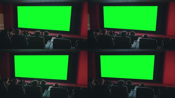 人们在电影院看大绿色屏幕欣赏电影