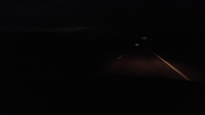开车行驶在漆黑的荒野公路上