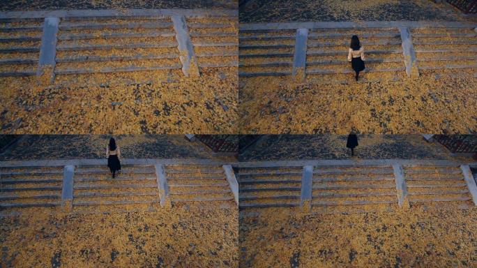 女孩走在落满银杏树叶的台阶上