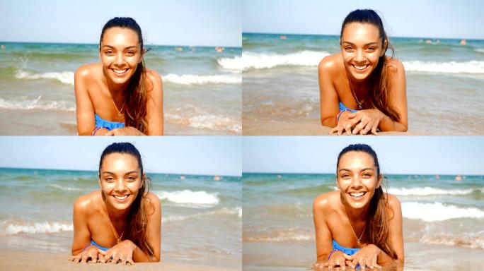 海滩上美丽的年轻女子躺在水里看着相机