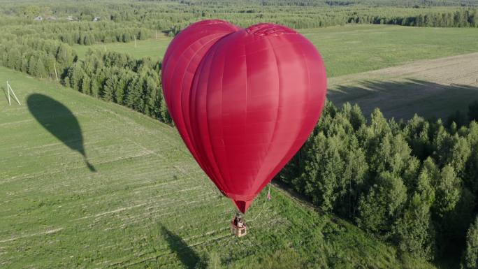 红色的爱心气球在田野上飞翔