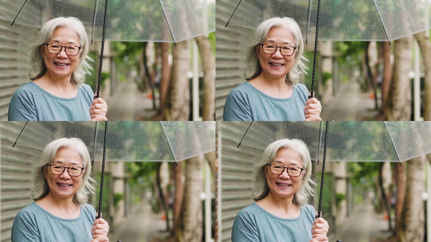 在城市雨天带着雨伞的老太太