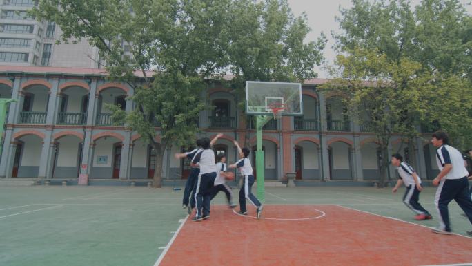在操场篮球场打篮球的高中学生