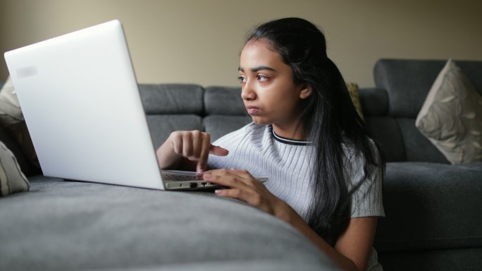 年轻女孩正在使用她的笔记本电脑