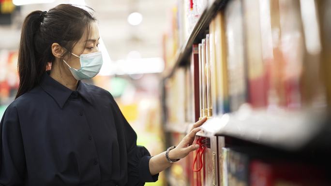 年轻中国女性戴着口罩在超市购物