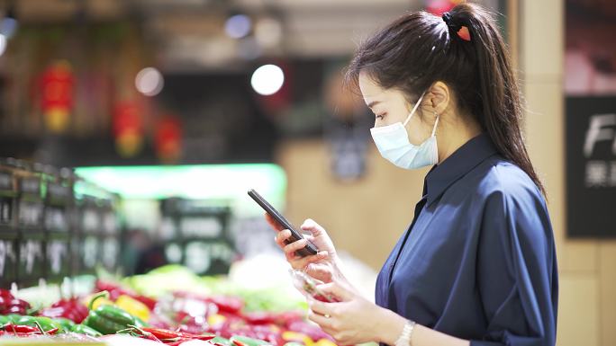 青年女性戴口罩超市购物使用手机