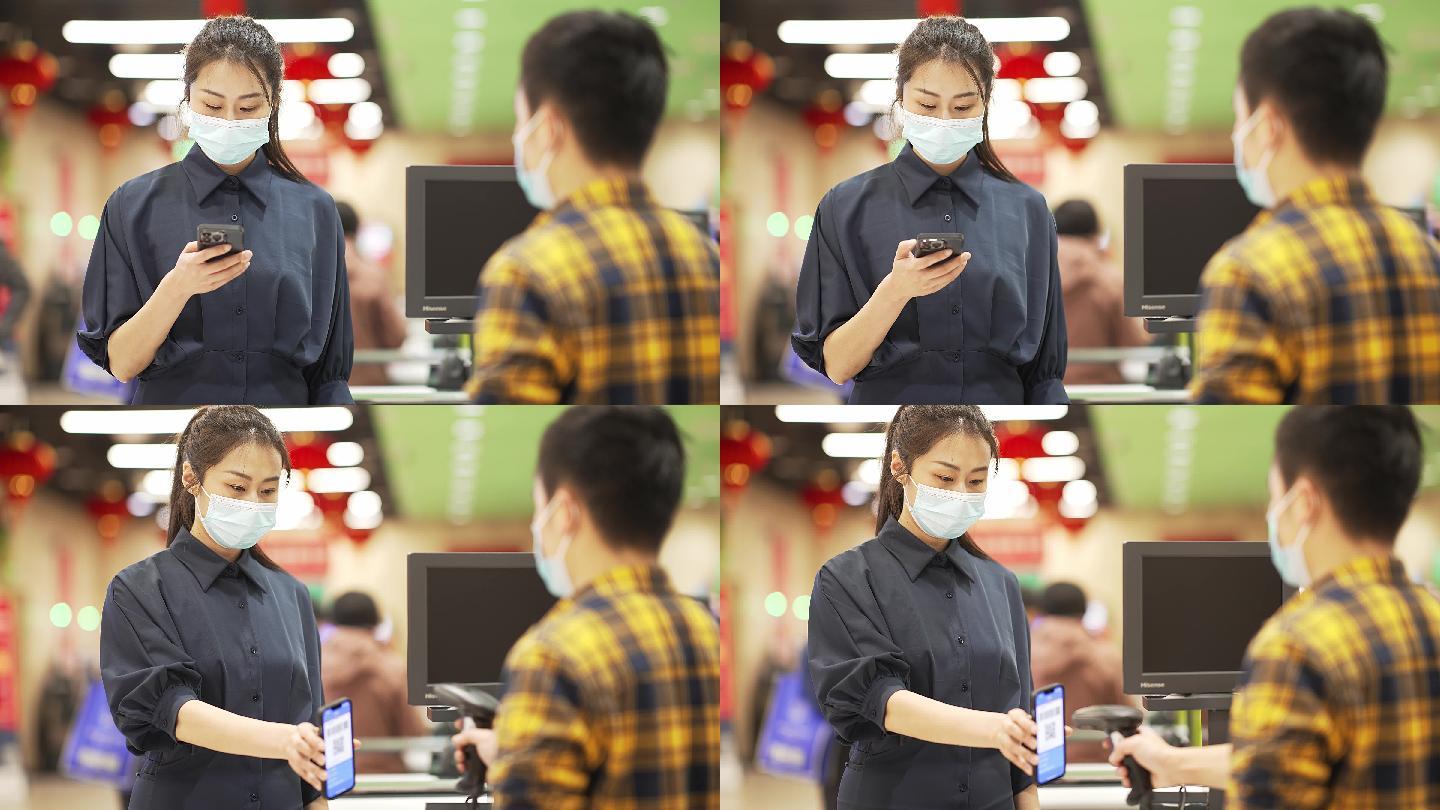 年轻女性戴着口罩在超市用手机支付
