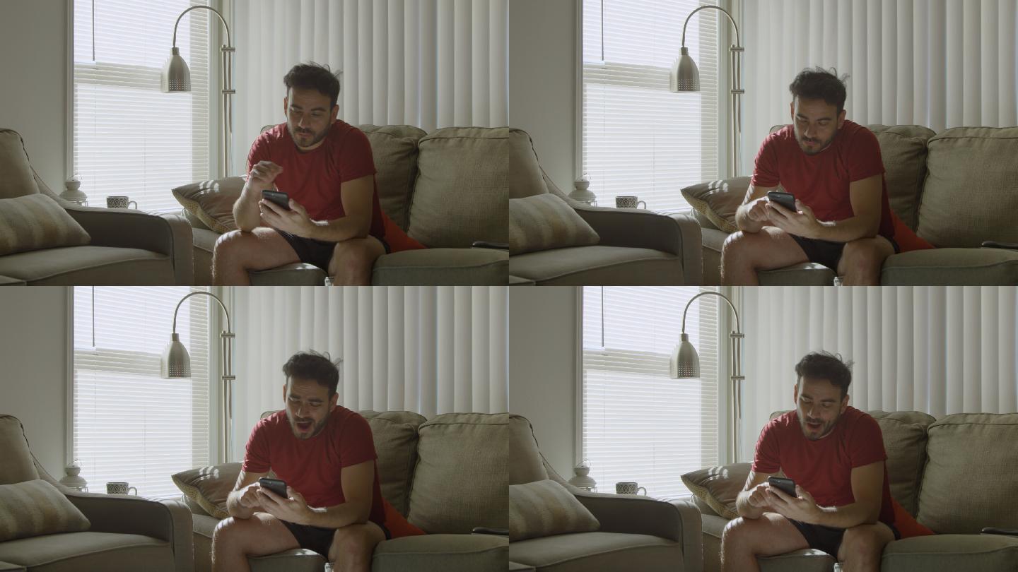 一个男人坐在家里的沙发上看手机