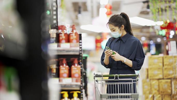 年轻女性戴着口罩在超市购物