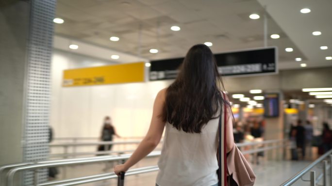 在机场行走的年轻女旅行者-戴着口罩