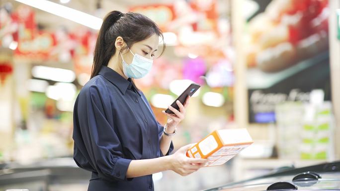 年轻中国女性在超市用手扫码查询信息